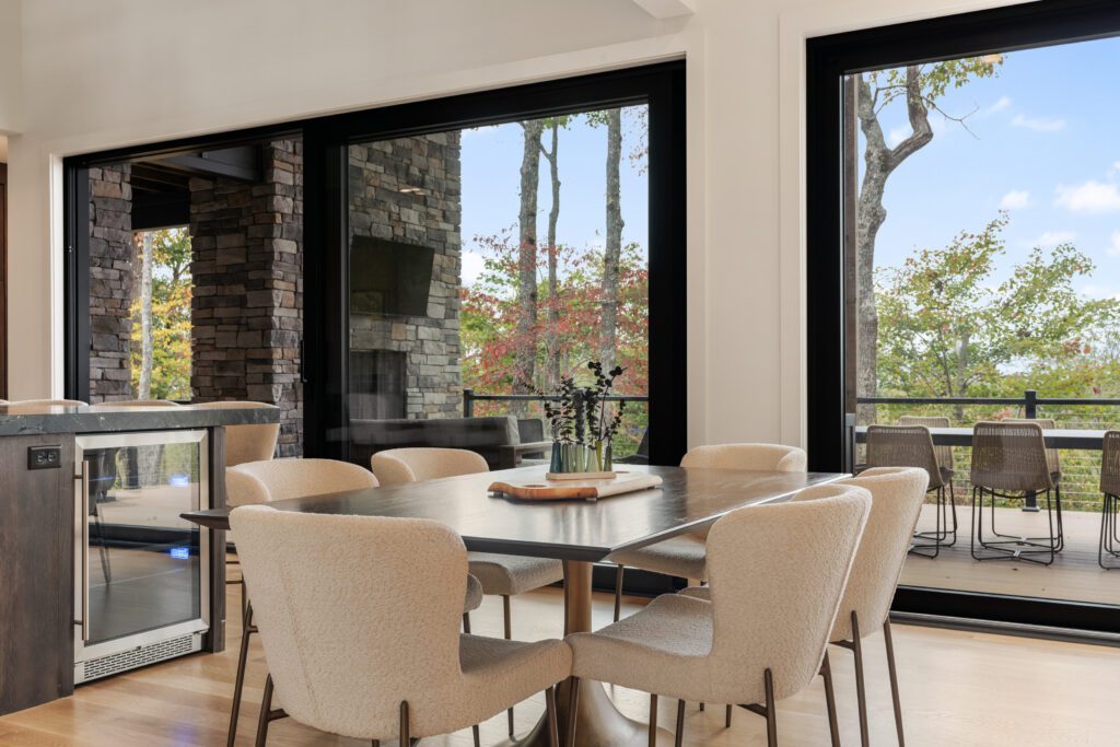 Elegant dining table at Wander Cedar Mountain with wall-to-wall glass doors opening to the outdoor deck