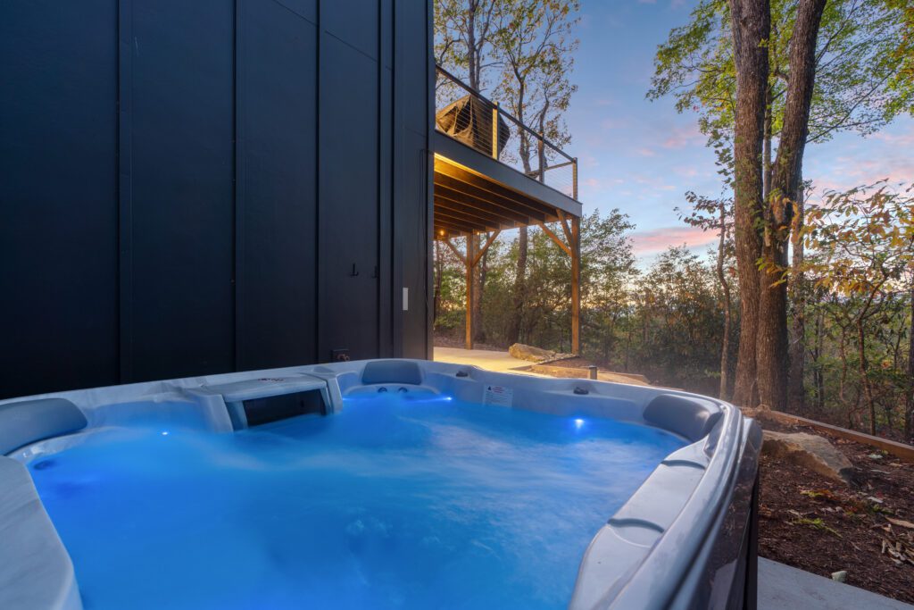 Private hot tub at Wander Cedar Mountain with views of the surrounding forest, towel rack, and foot-washing station.